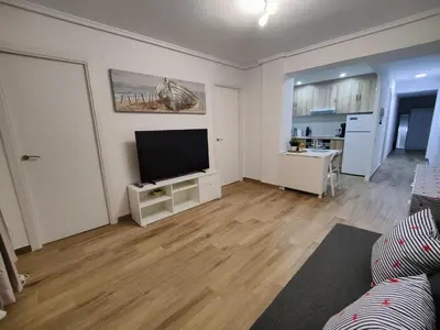 a living room with a flat screen tv and a kitchen at Near Beach Cullera in Cullera