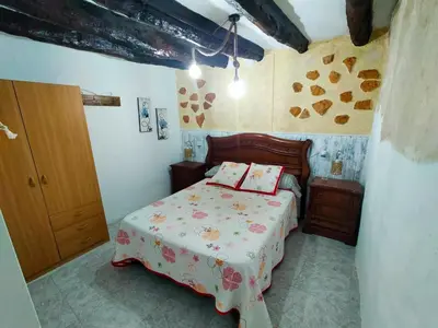 a small bedroom with a bed and a wooden door at Casa de pueblo García Marquez in Geldo