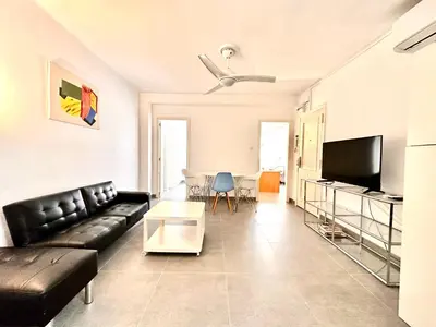 a living room with a black leather couch and a table at Malvarrosa Beach in Valencia