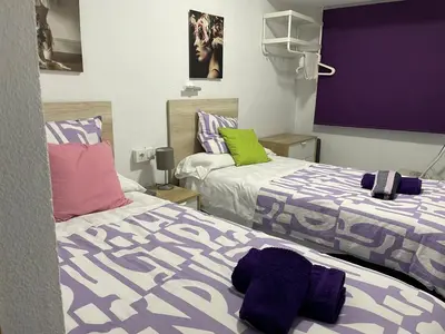 two beds in a room with purple and green at Albahicín in Puerto de Sagunto