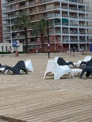 a row of white benches on a beach at Apartamento 100 metros Playa San Antonio CULLERA in Cullera