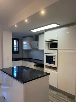 a kitchen with white cabinets and a black counter top at comfortable apartment in an elite area with a beautiful veranda in Port Saplaya