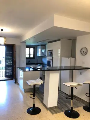 a kitchen with a counter and two bar stools at comfortable apartment in an elite area with a beautiful veranda in Port Saplaya