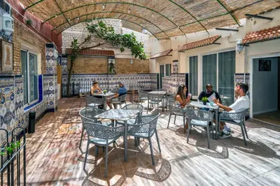 a group of people sitting at tables on a patio at SOM Hostel Valencia in Valencia