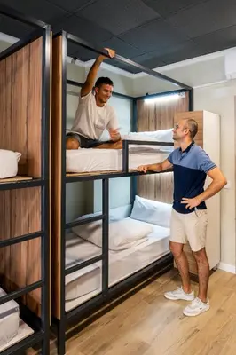 two men are standing in front of bunk beds at SOM Hostel Valencia in Valencia