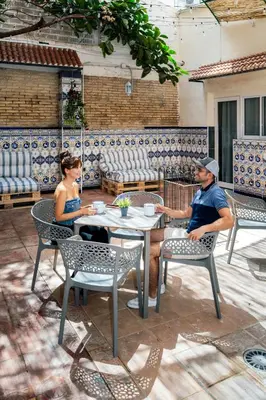 a man and woman sitting at a table on a patio at SOM Hostel Valencia in Valencia