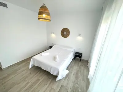 a white bedroom with a bed and a chandelier at NUEVO, a 80 metros del mar y la playa in Cullera