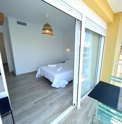 a bedroom with a bed and a sliding glass door at NUEVO, a 80 metros del mar y la playa in Cullera