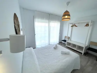 a white bedroom with a bed and a mirror at NUEVO, a 80 metros del mar y la playa in Cullera
