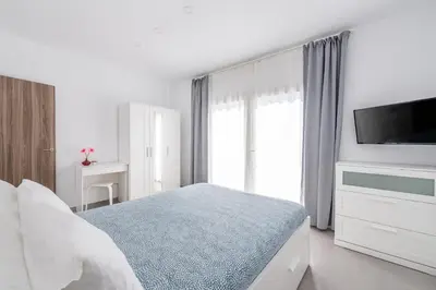 a white bedroom with a bed and a flat screen tv at Vilamercat in Sueca