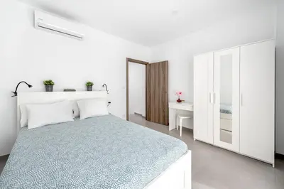 a white bedroom with a bed and a desk at Vilamercat in Sueca