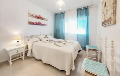 a white bedroom with a bed and a chair at 1 Bedroom Nice Apartment In Cullera in Cullera