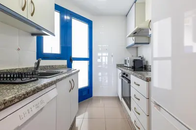 a kitchen with white cabinets and a blue door at ApartUP Patacona Surfing Beach in Valencia