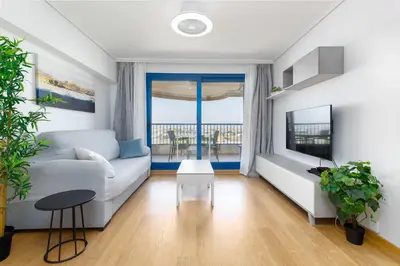 a living room with a white couch and a tv at ApartUP Patacona Surfing Beach in Valencia