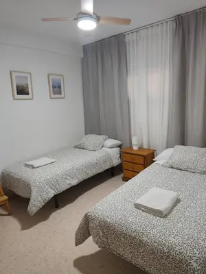 a bedroom with two beds and a ceiling fan at El Cisne frente al mar- Piscina y Wifi in Cullera