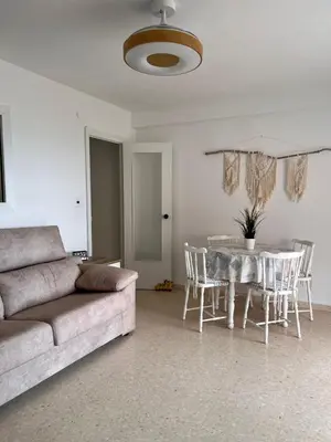a living room with a couch and a table and chairs at El Cisne frente al mar- Piscina y Wifi in Cullera