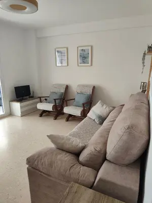 a living room with a brown couch and two chairs at El Cisne frente al mar- Piscina y Wifi in Cullera