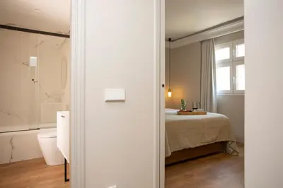 a bedroom with a bed and a bathroom with a window at SingularStays Ático Reina Catalina in Valencia