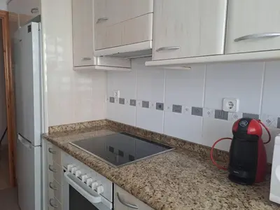 a kitchen with white cabinets and a counter top at Cullera apartamento junto al mar in Cullera