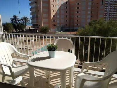 a white table and chairs on a balcony with the beach at Cullera apartamento junto al mar in Cullera