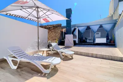 two lounge chairs and an umbrella on a patio at Cueva con jacuzzi a 20 minutos de Valencia in Benaguacil