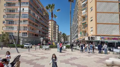 a group of people walking in a city with tall buildings at Apartamento Horizonte Azul Cullera in Cullera