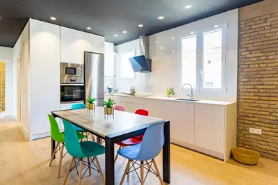 a kitchen with a wooden table and colorful chairs at Private room Beach Valencia in Valencia