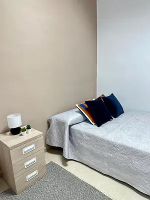 a bedroom with a bed and a wooden nightstand with a blue pillow at The Valencia Stop in Valencia