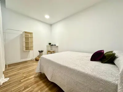 a white bedroom with a bed and a wooden floor at The Valencia Stop in Valencia