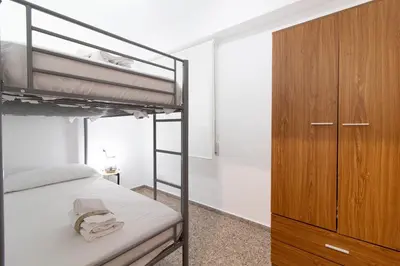 a bedroom with two bunk beds and a wooden cabinet at Global Vacacional, Practico apartamento para 6 personas en Puerto Sagunto in Puerto de Sagunto