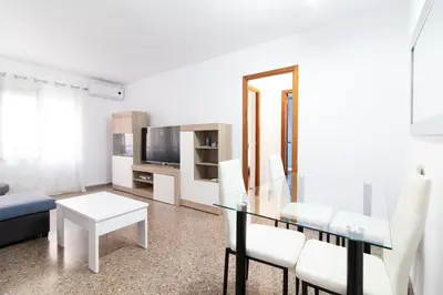 a living room with a glass table and white chairs at Global Vacacional, Practico apartamento para 6 personas en Puerto Sagunto in Puerto de Sagunto