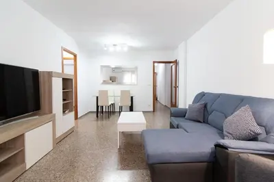 a living room with a blue couch and a tv at Global Vacacional, Practico apartamento para 6 personas en Puerto Sagunto in Puerto de Sagunto