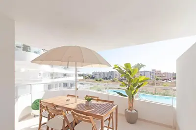 a dining table with an umbrella on a balcony at Global Vacacional, Apartamento con 2 terrazas en Gran Canet in Canet de Berenguer