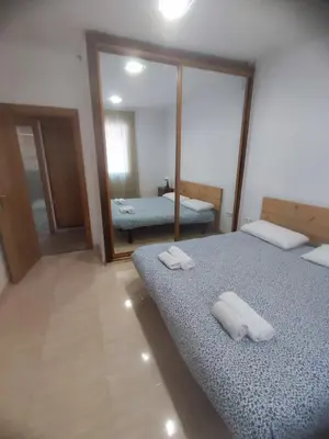 a bedroom with two beds and a mirror at Planta baja, bien comunicada, cerca de la playa. in Valencia