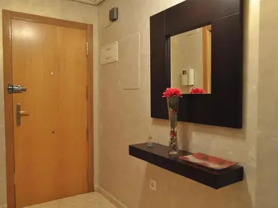 a bathroom with a door and a mirror and a vase with flowers at Acogedor apartamento en Burriana centro in Burriana