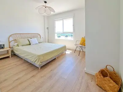 a bedroom with a bed and a table and a window at Charming flat close to the beach in Canet de Berenguer