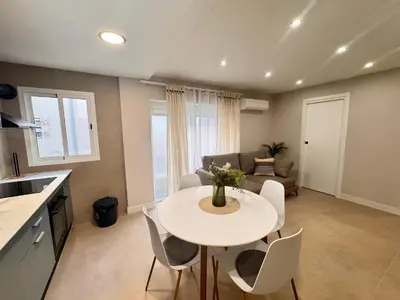 a kitchen and living room with a white table and chairs at cultura y playa in Puerto de Sagunto