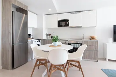 a kitchen with a white table and white chairs at Global Vacacional, Bonito apartamento con terraza en Gran Canet in Canet de Berenguer