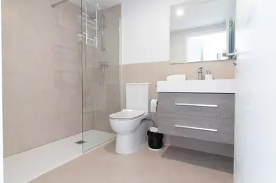 a bathroom with a toilet and a glass shower at Global Vacacional, Nuevo apartamento con terraza en Gran Canet Residencial in Canet de Berenguer