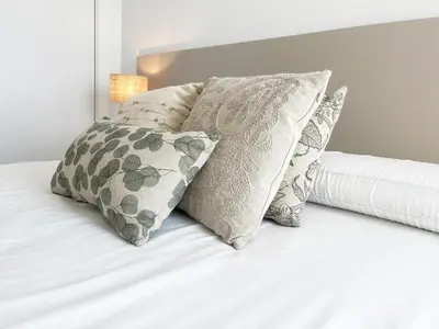 a bed with four pillows and a white bedspread at Global Vacacional, Nuevo apartamento con terraza en Gran Canet Residencial in Canet de Berenguer