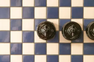 three black buttons on a blue and white tiles at El Rincón de María Vicenta in Valencia