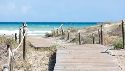 a wooden path to the beach with the ocean in the background at V&M Canet in Canet de Berenguer