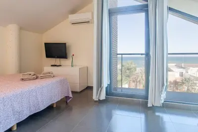 a bedroom with a bed and a tv and a large window at Confortable Beach Appartment with Views to the Sea in Puzol