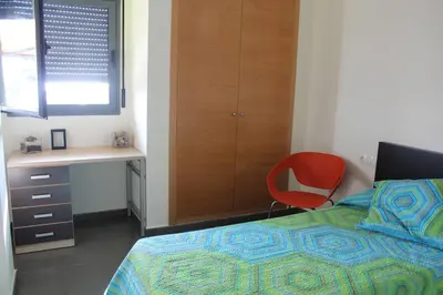 a bedroom with a bed and a desk and a red chair at Confortable Beach Appartment with Views to the Sea in Puzol