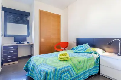 a bedroom with a bed with a desk and a red chair at Confortable Beach Appartment with Views to the Sea in Puzol