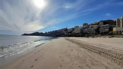 a beach with footprints in the sand and the ocean at Faro Cullera primera Linea Playa del Dosel in Faro de Cullera