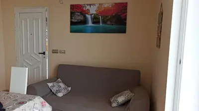 a living room with a couch and a painting on the wall at Faro Cullera primera Linea Playa del Dosel in Faro de Cullera