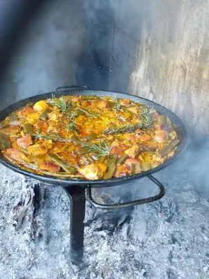 a pizza is cooking on a pan on a grill at Faro Cullera primera Linea Playa del Dosel in Faro de Cullera