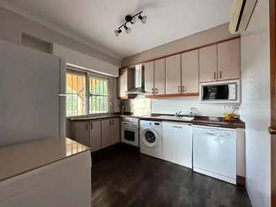 a kitchen with white cabinets and a washer and dryer at Villa les palmiers in Rafelguaraf