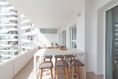 a white dining room with a white table and stools at Gran Apartment in Canet de Berenguer